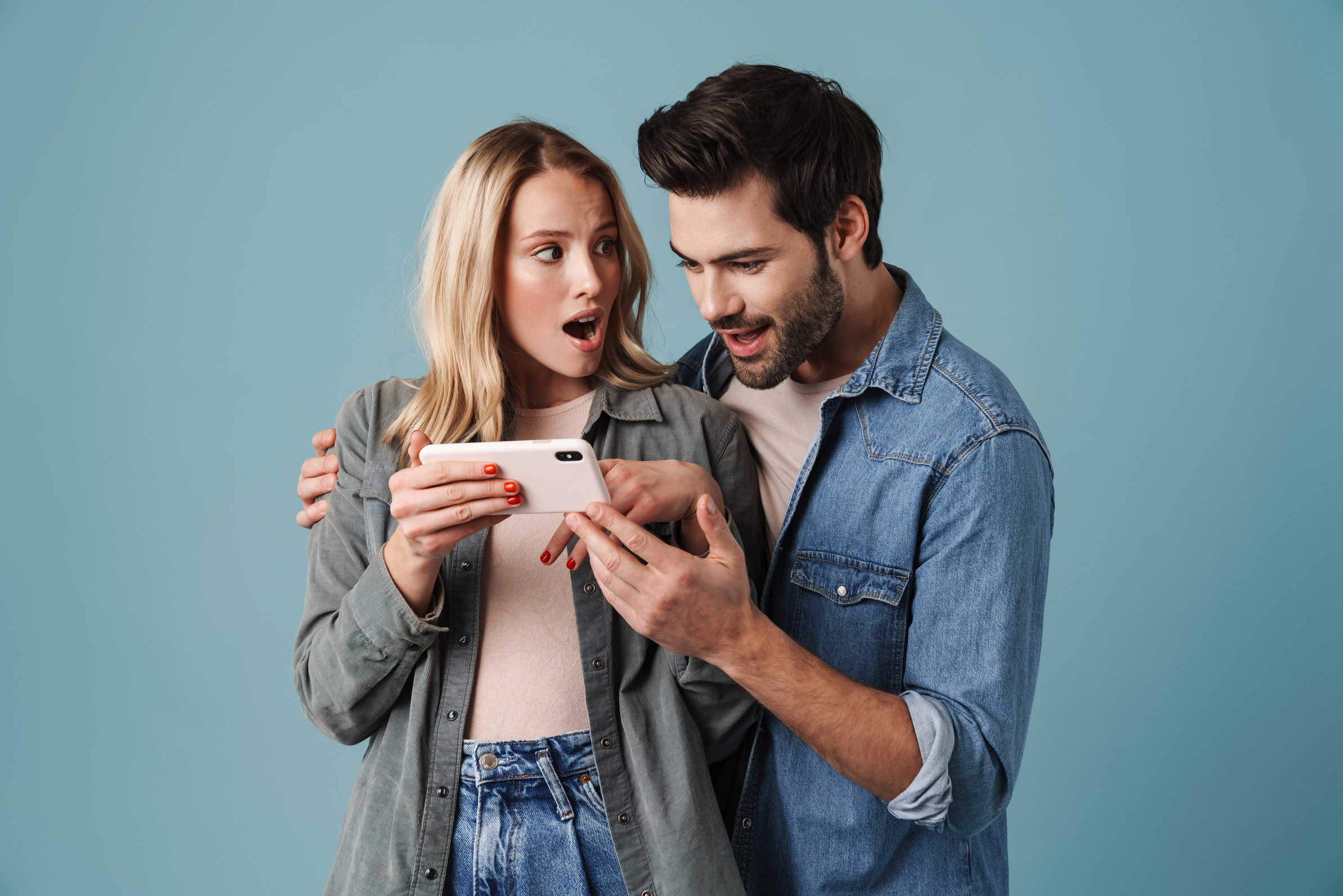 Young Surprised Man and Woman Hugging and Using Mobile Phone